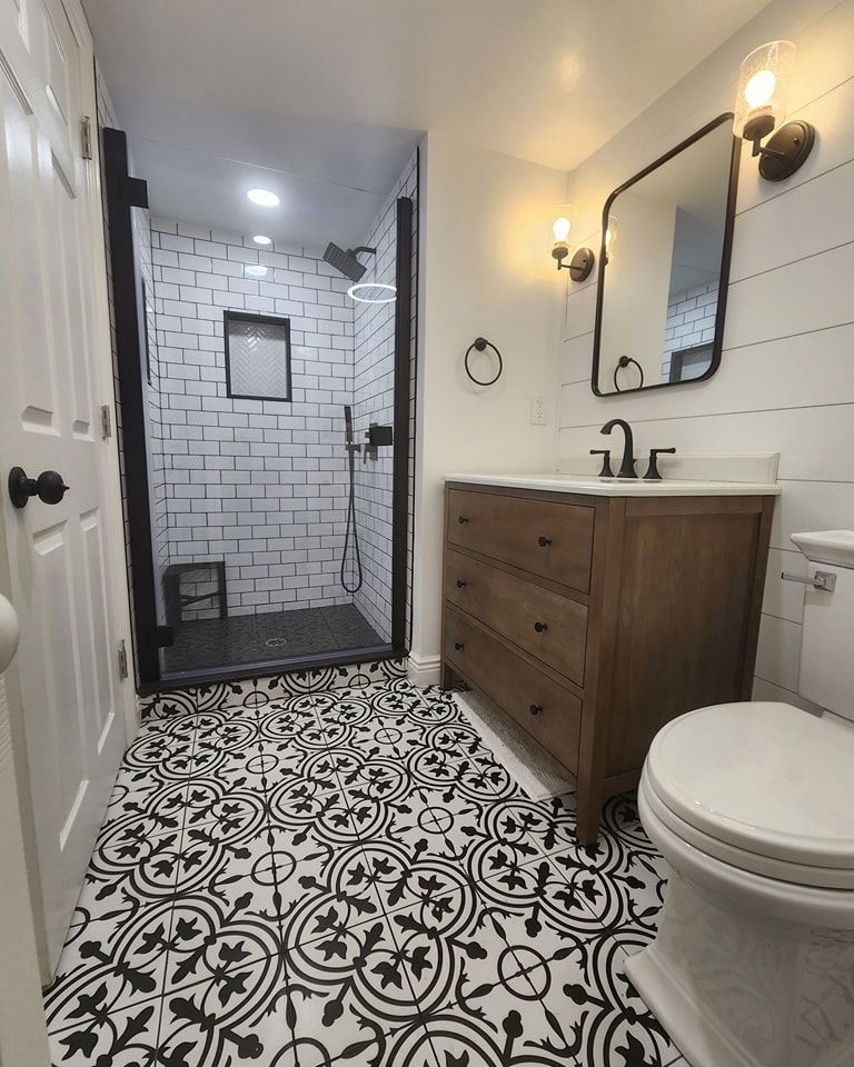 A bathroom with a sink, toilet, shower, and mirror