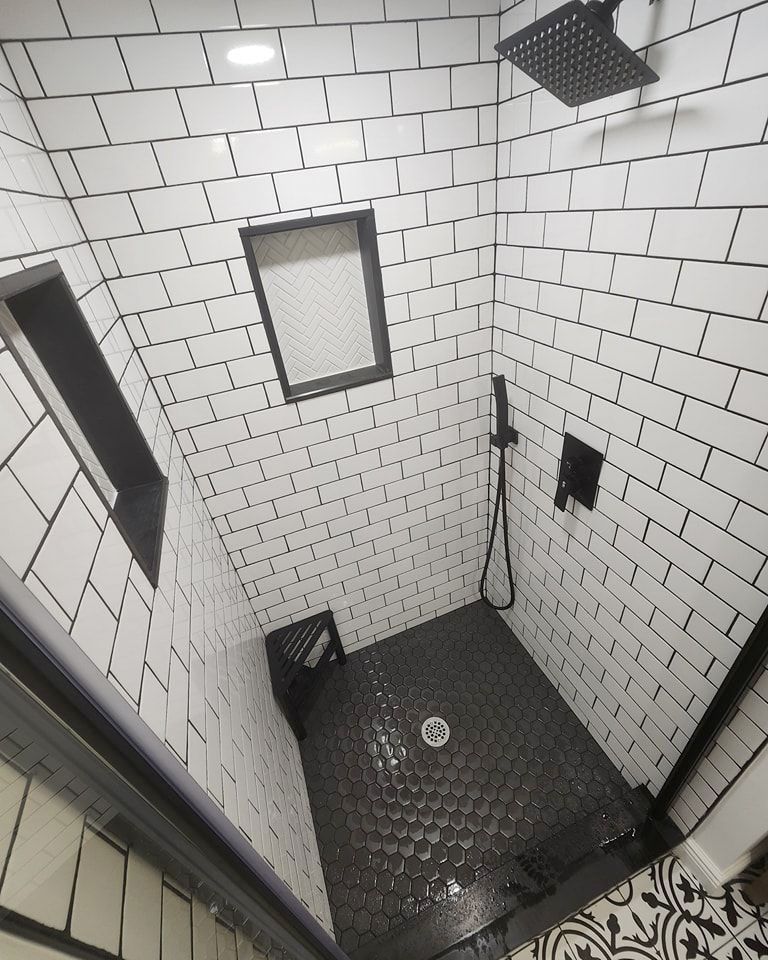 Top view of a shower with white tiles and a black floor