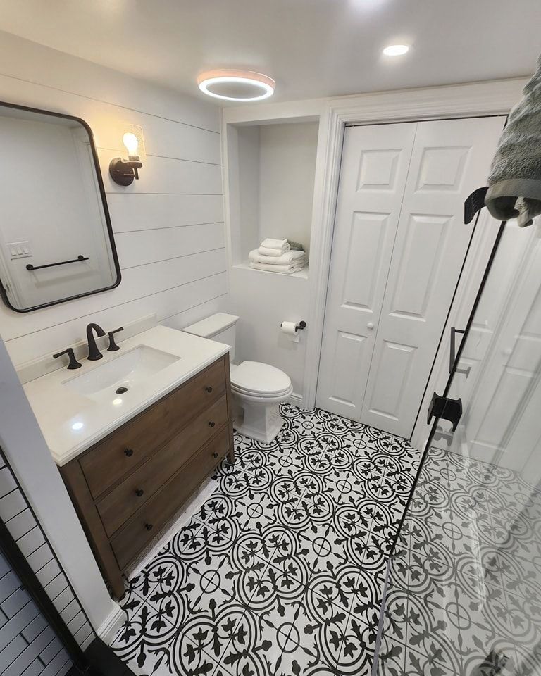 A bathroom with a mirror, sink, toilet, and walk-in shower