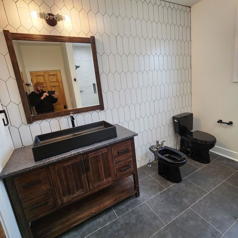 A bathroom with a sink, toilet, and mirror.