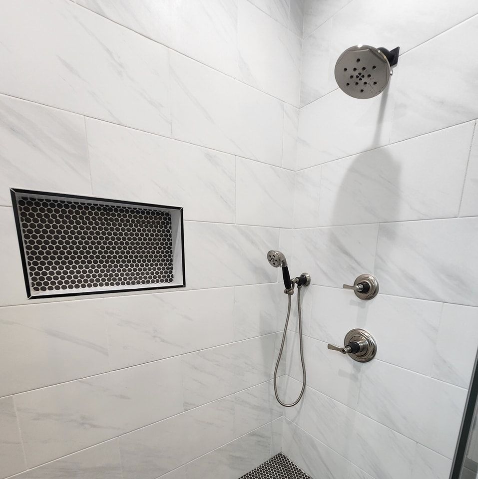 A shower with a shower head and a shelf in the wall