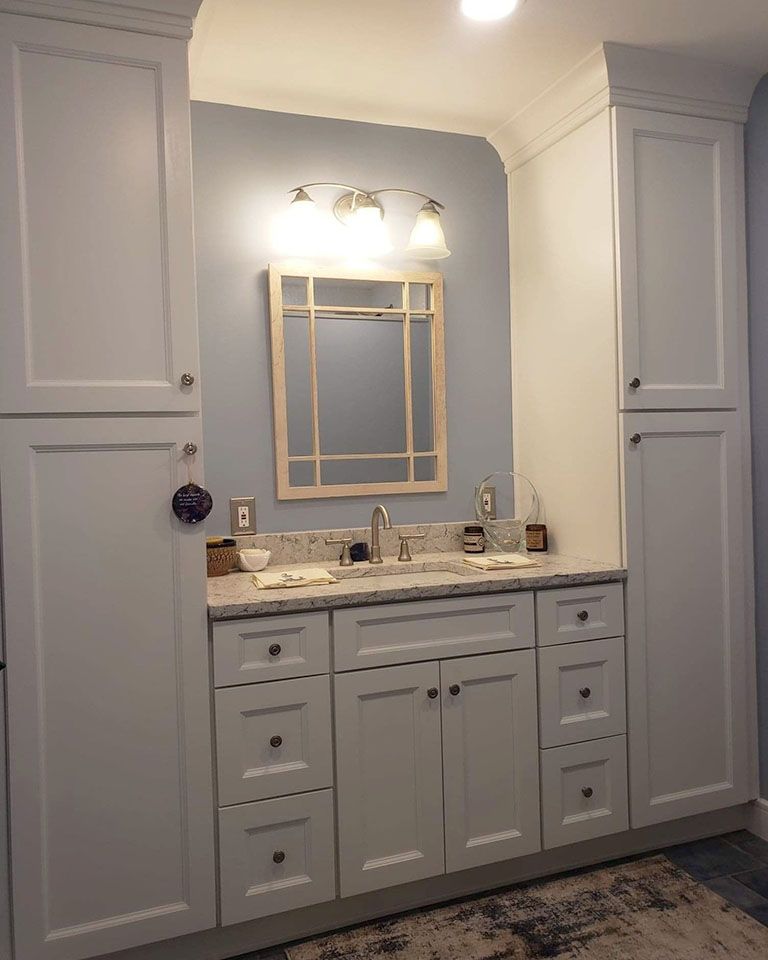 A bathroom with two sinks, a mirror, and white cabinets