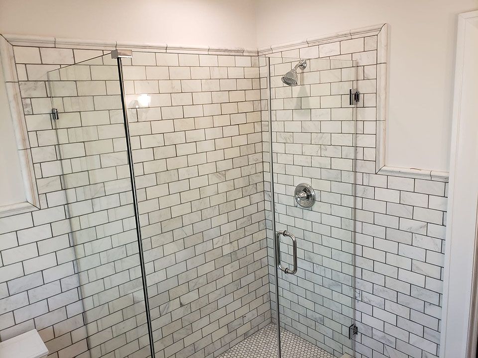 A bathroom with white tiles and a glass shower door