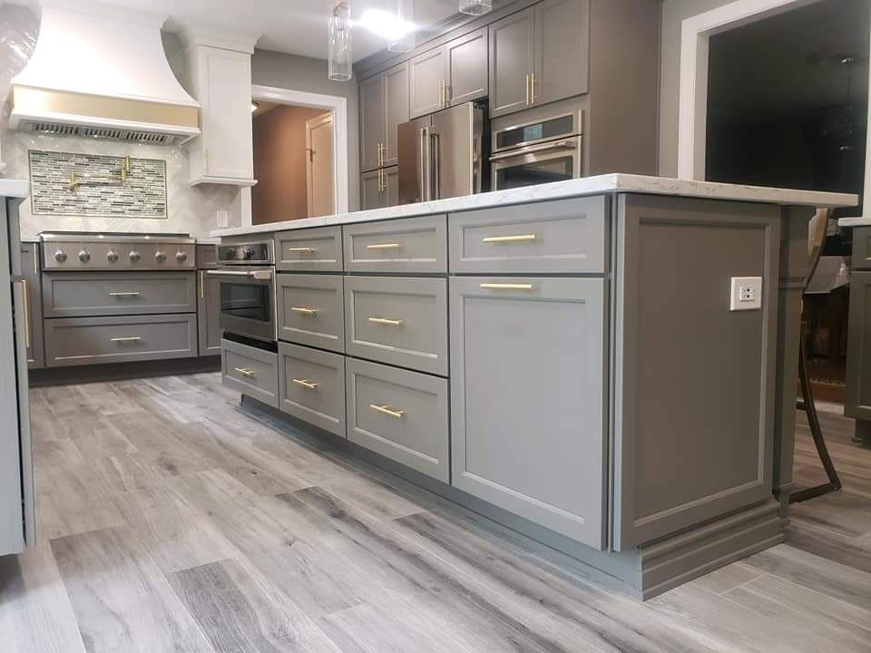 A kitchen with gray cabinets, stainless steel appliances, and a large island