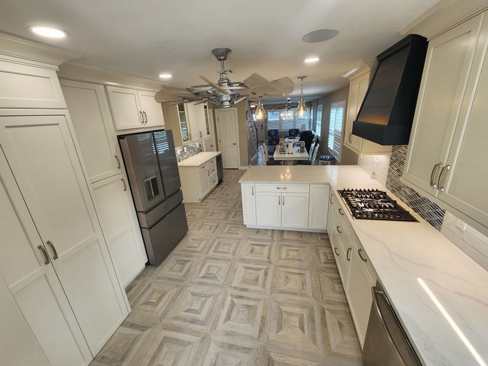A kitchen with white cabinets, a stove, a refrigerator, and a ceiling fan
