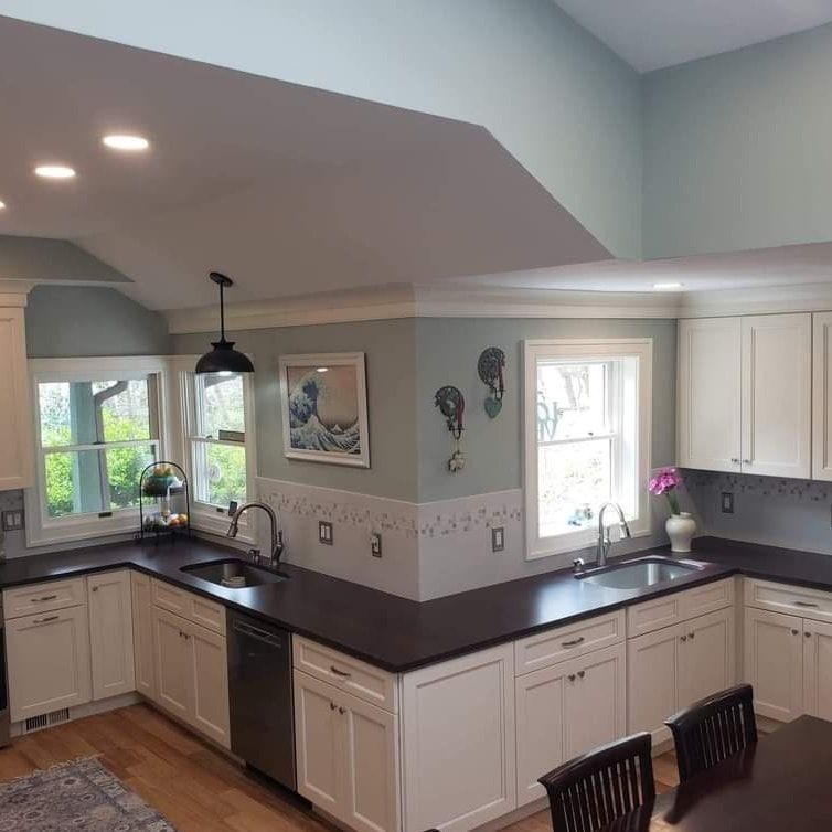 A kitchen with white cabinets, dark countertops, and two sinks