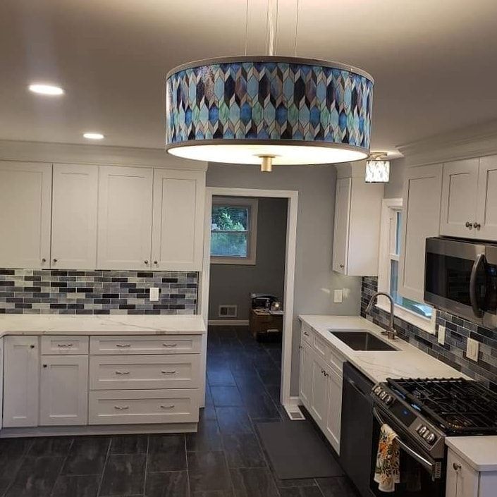 A kitchen with white cabinets, a stove, a sink, and a chandelier