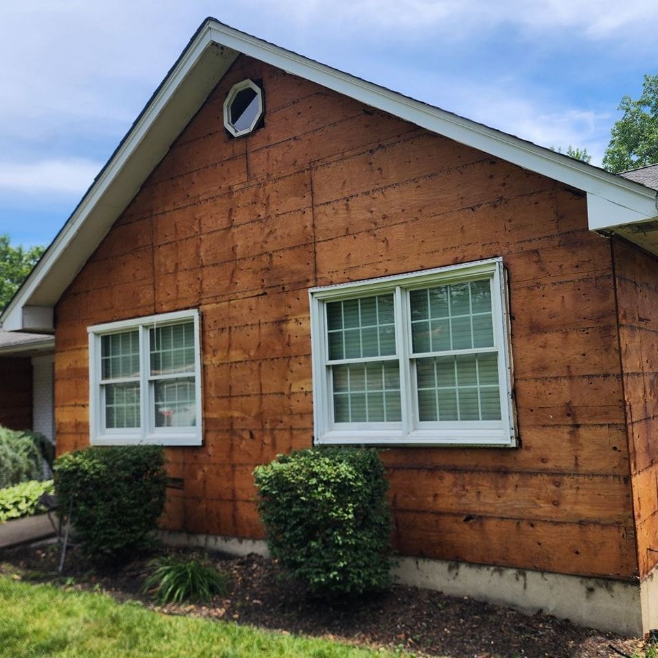 A brown house with white windows and a round window on the roof