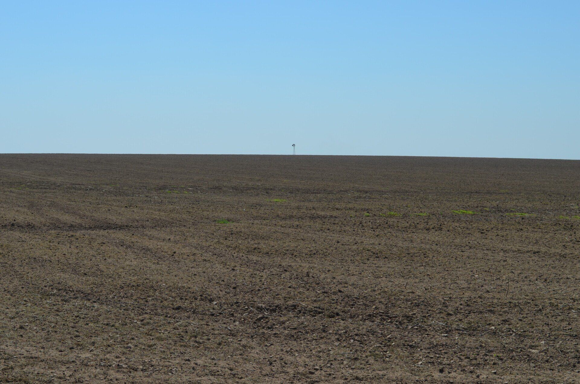 A large empty field with a blue sky in the background.