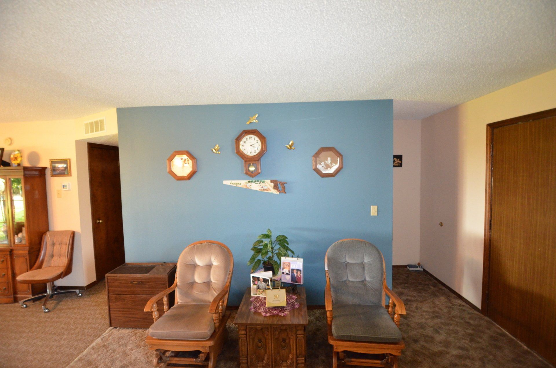 A living room with two chairs and a clock on the wall