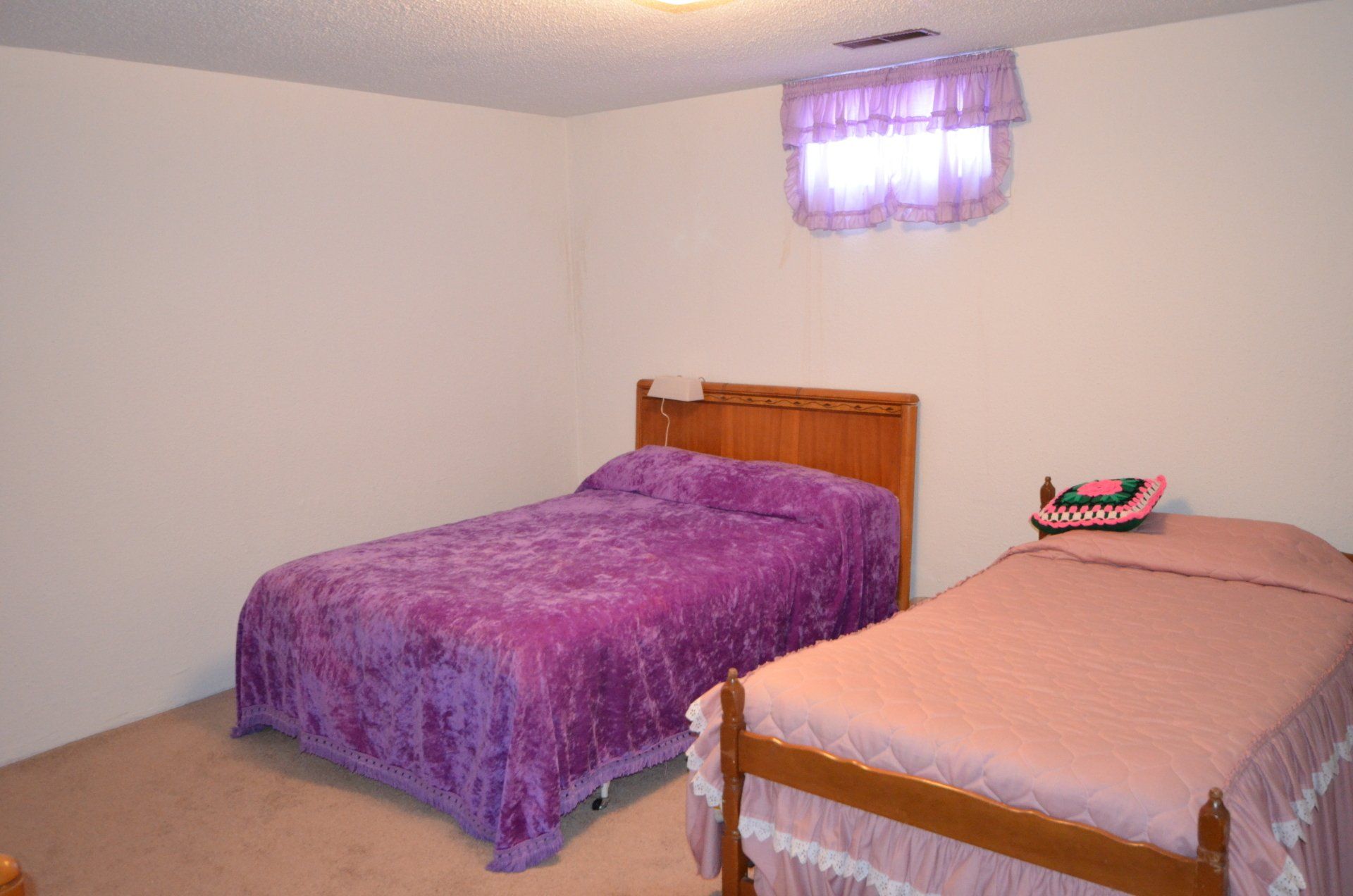 A bedroom with two beds and a window with purple curtains