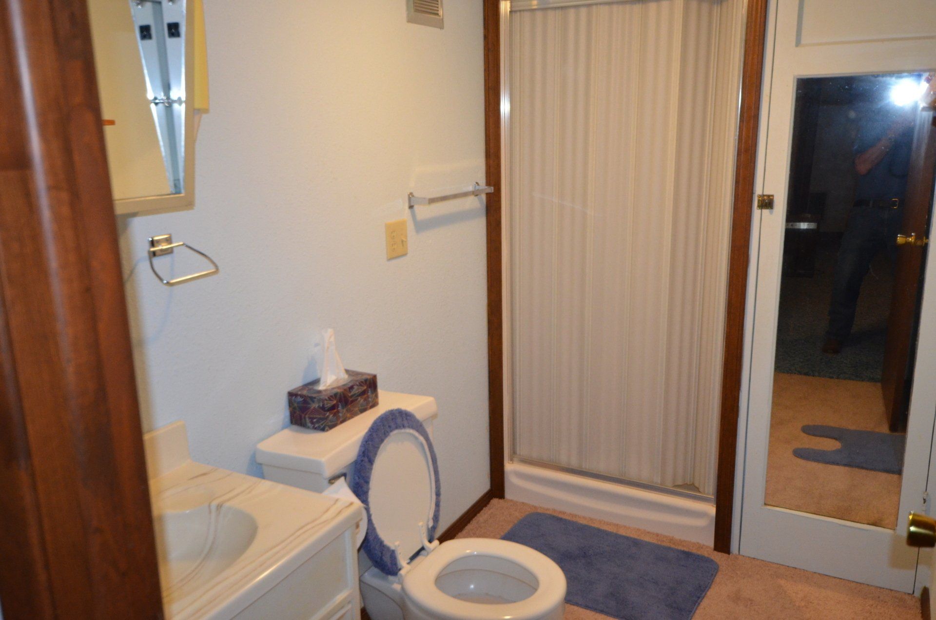 A bathroom with a toilet , sink and shower.