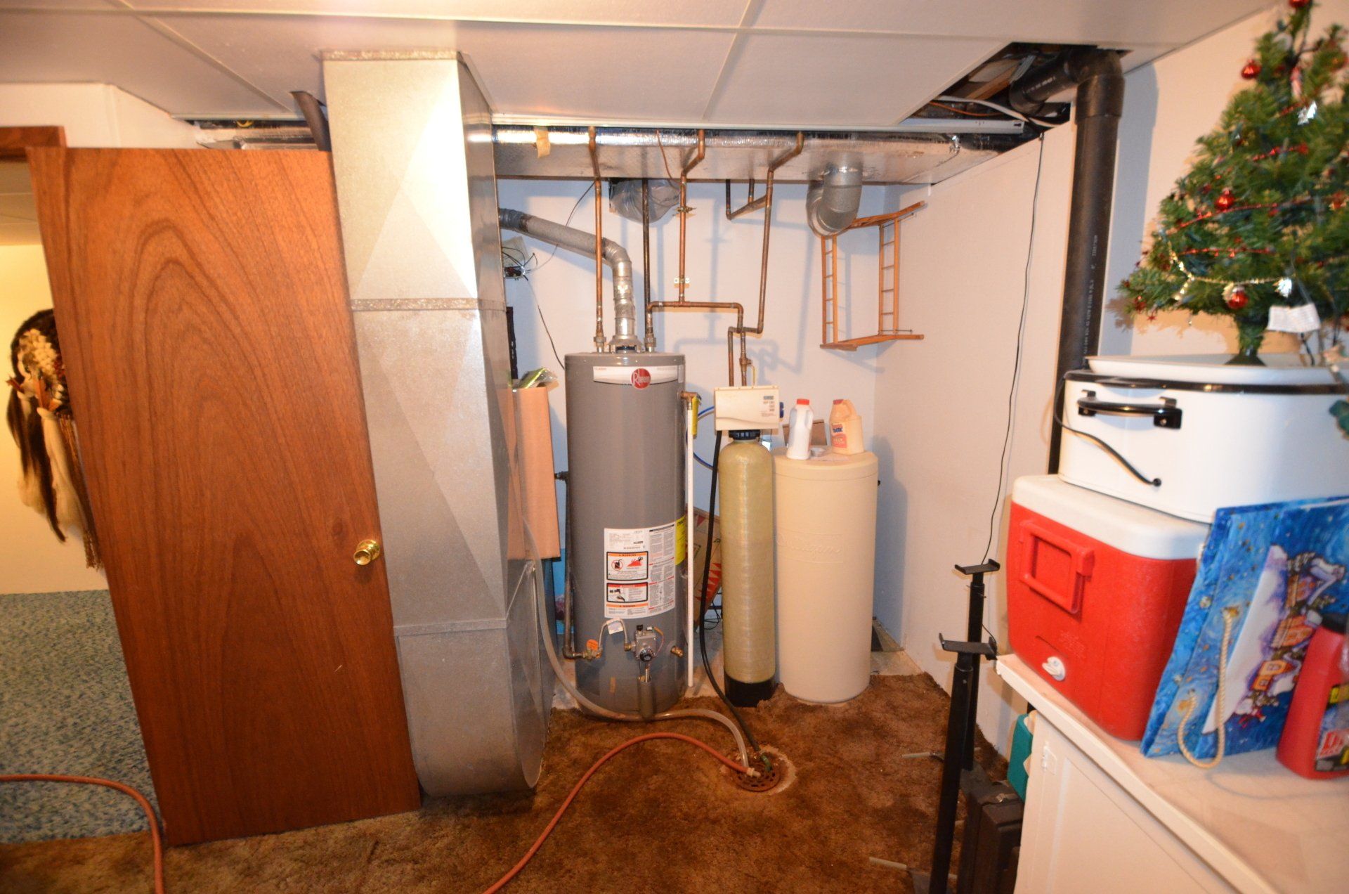 A basement with a water heater and a christmas tree.