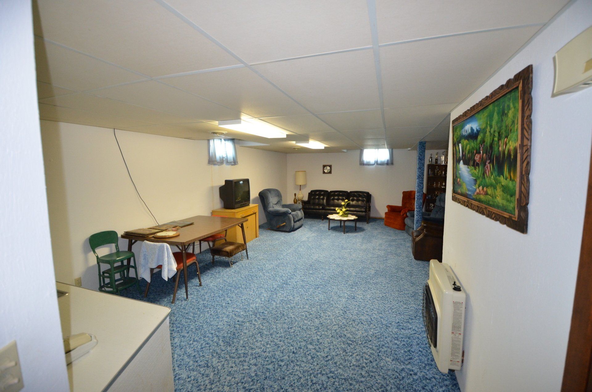A living room with blue carpet and a picture on the wall