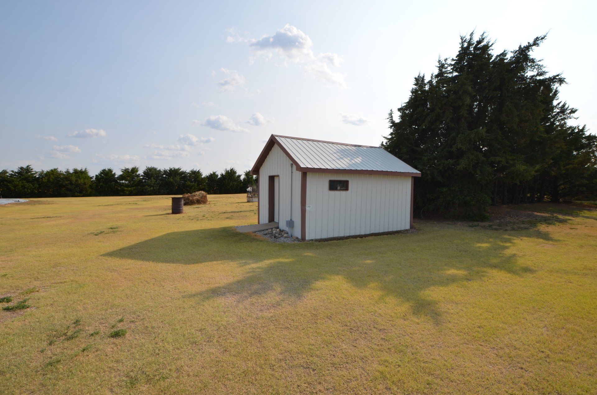 A small white shed in the middle of a grassy field