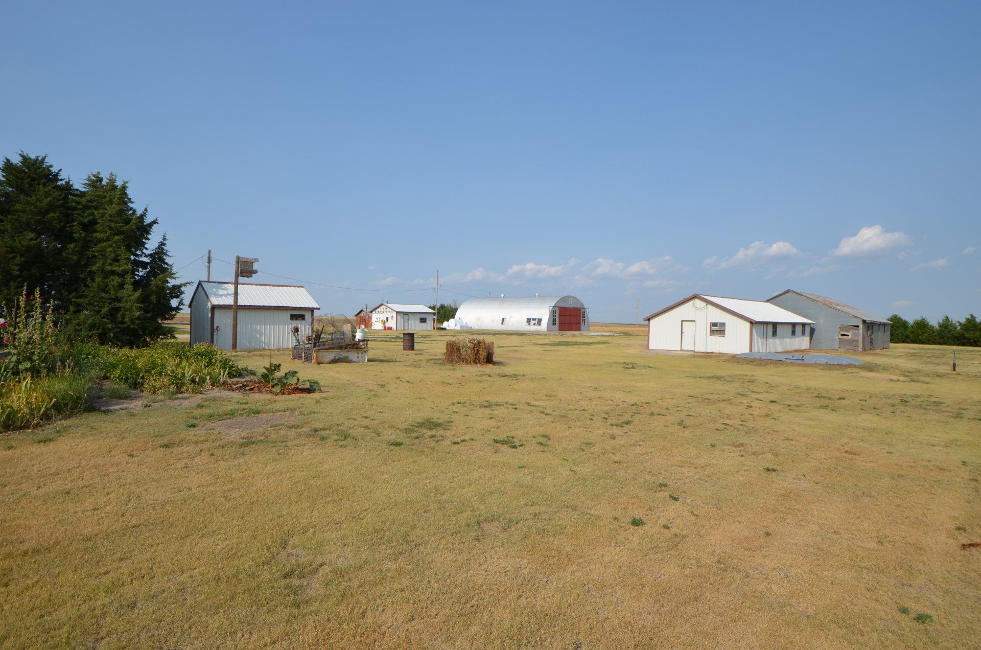 A farm with a lot of buildings and hay bales