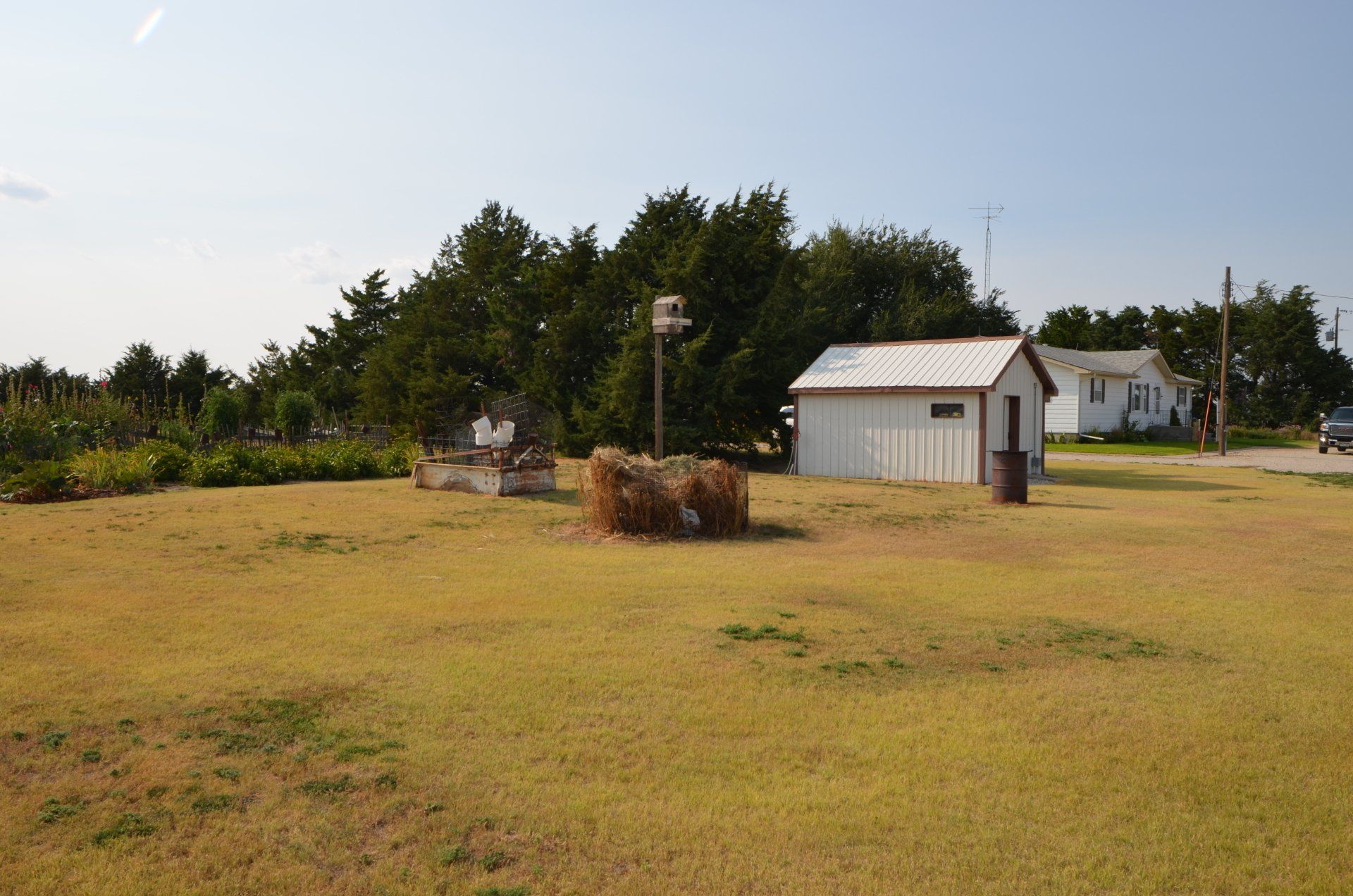 A small white shed sits in the middle of a grassy field