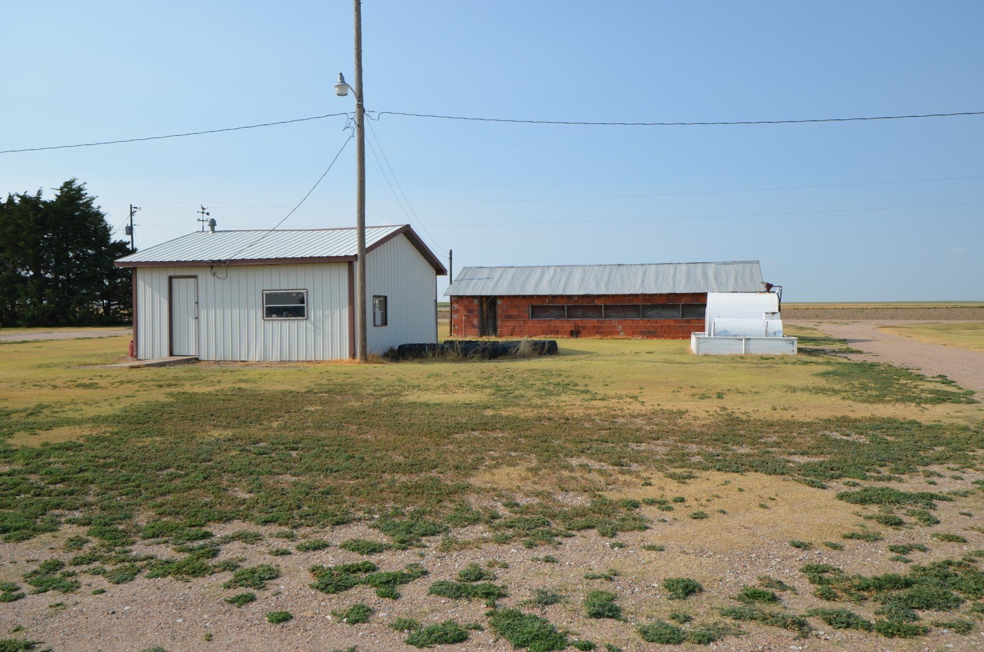 A small white building sits in the middle of a grassy field