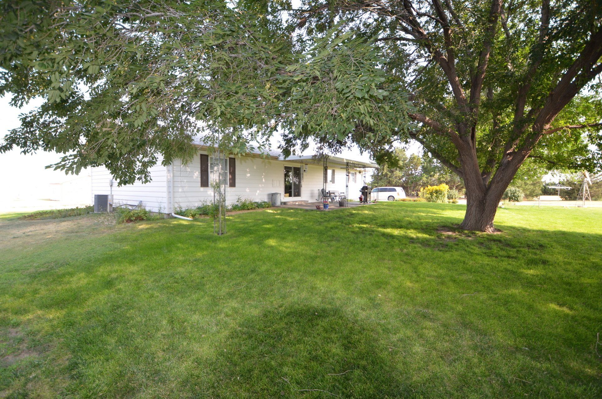 A white house with a large lawn and a tree in front of it.