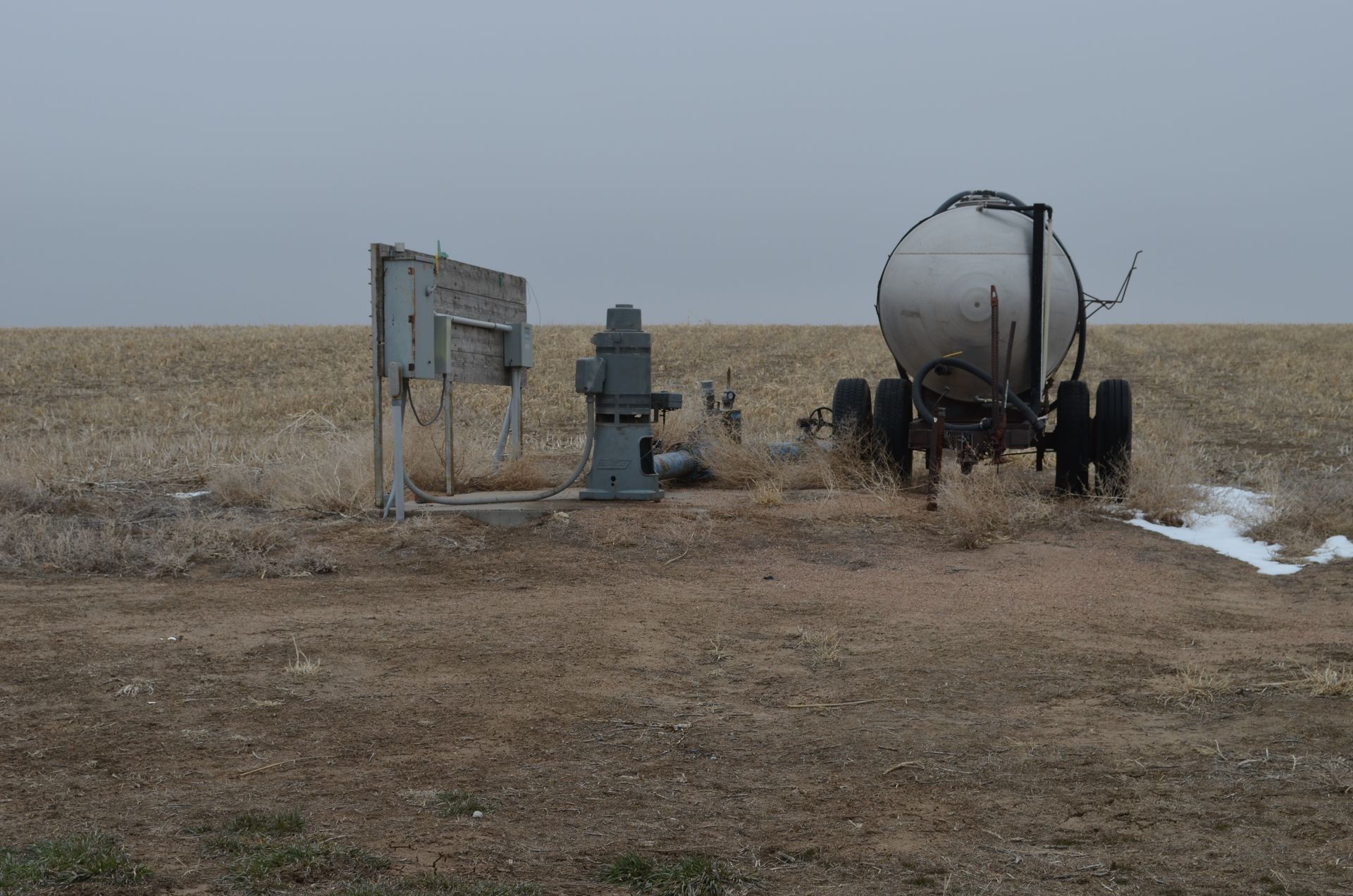 A tanker truck is parked in the middle of a field.