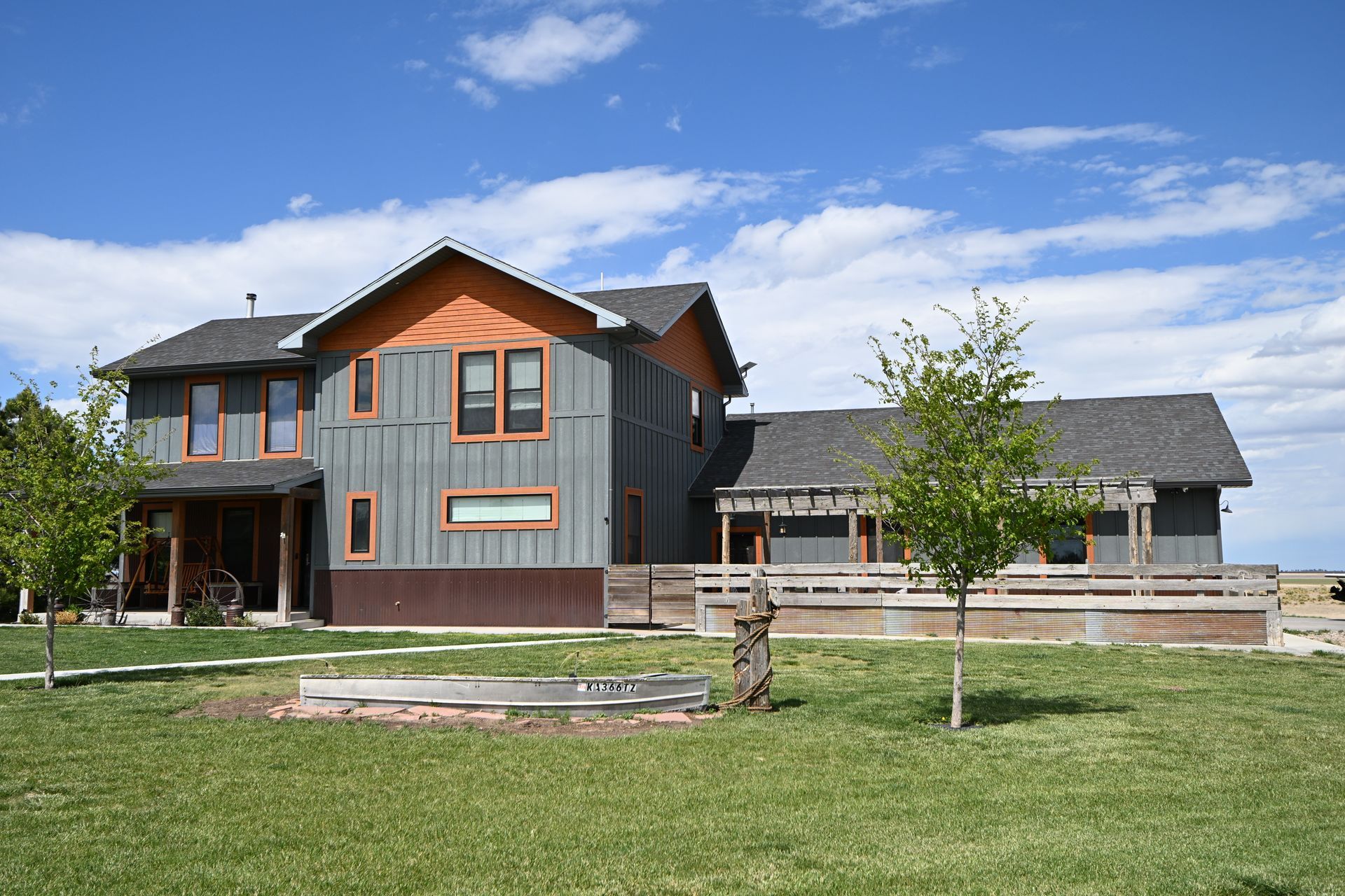 Modern two-story house with wood accents and a large lawn under a blue sky