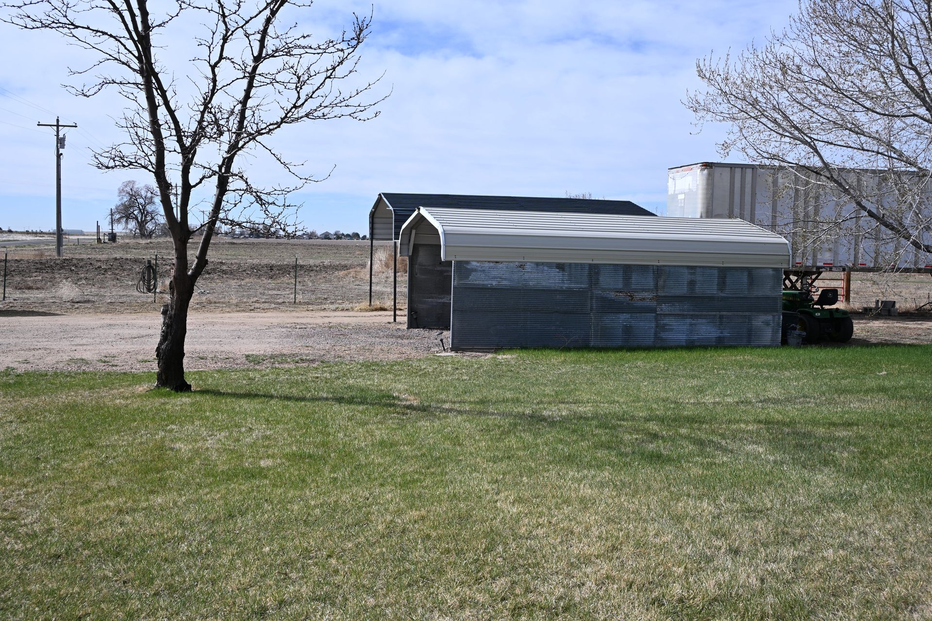 Small farm shed with a metal roof in a grassy field under a clear sky.