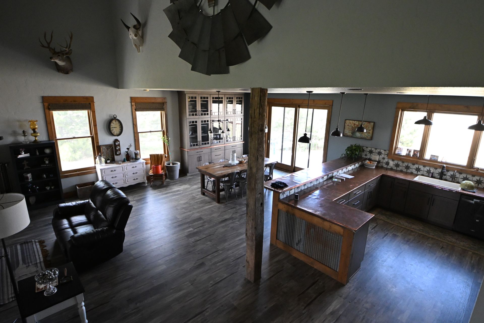 Wide kitchen and living area with dark wood floors, a large island, and bright windows