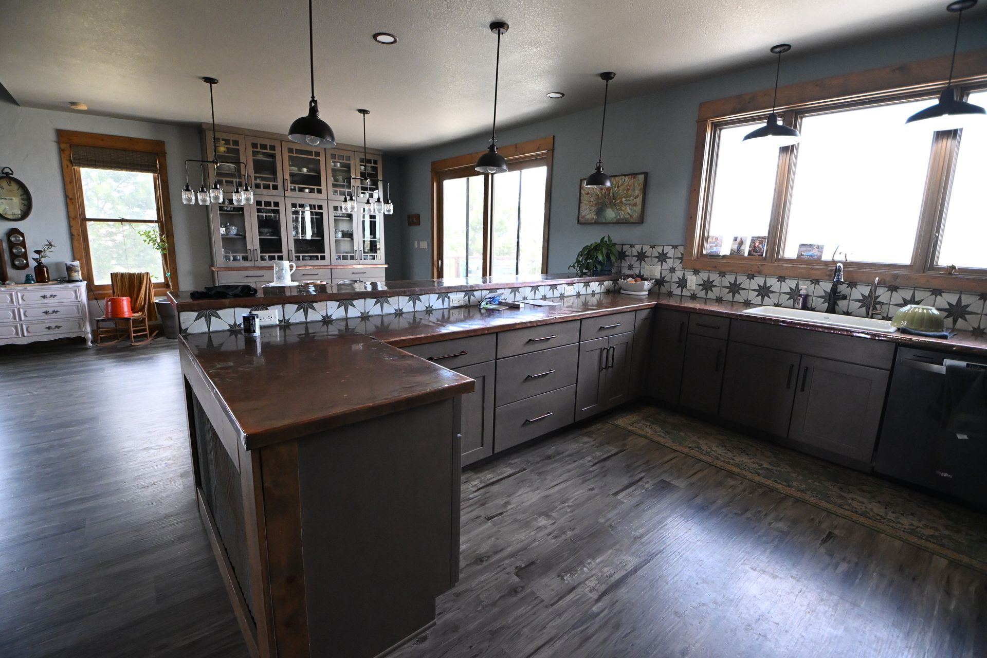 Spacious modern kitchen with dark wood cabinets, large island, and wood floors under pendant lights
