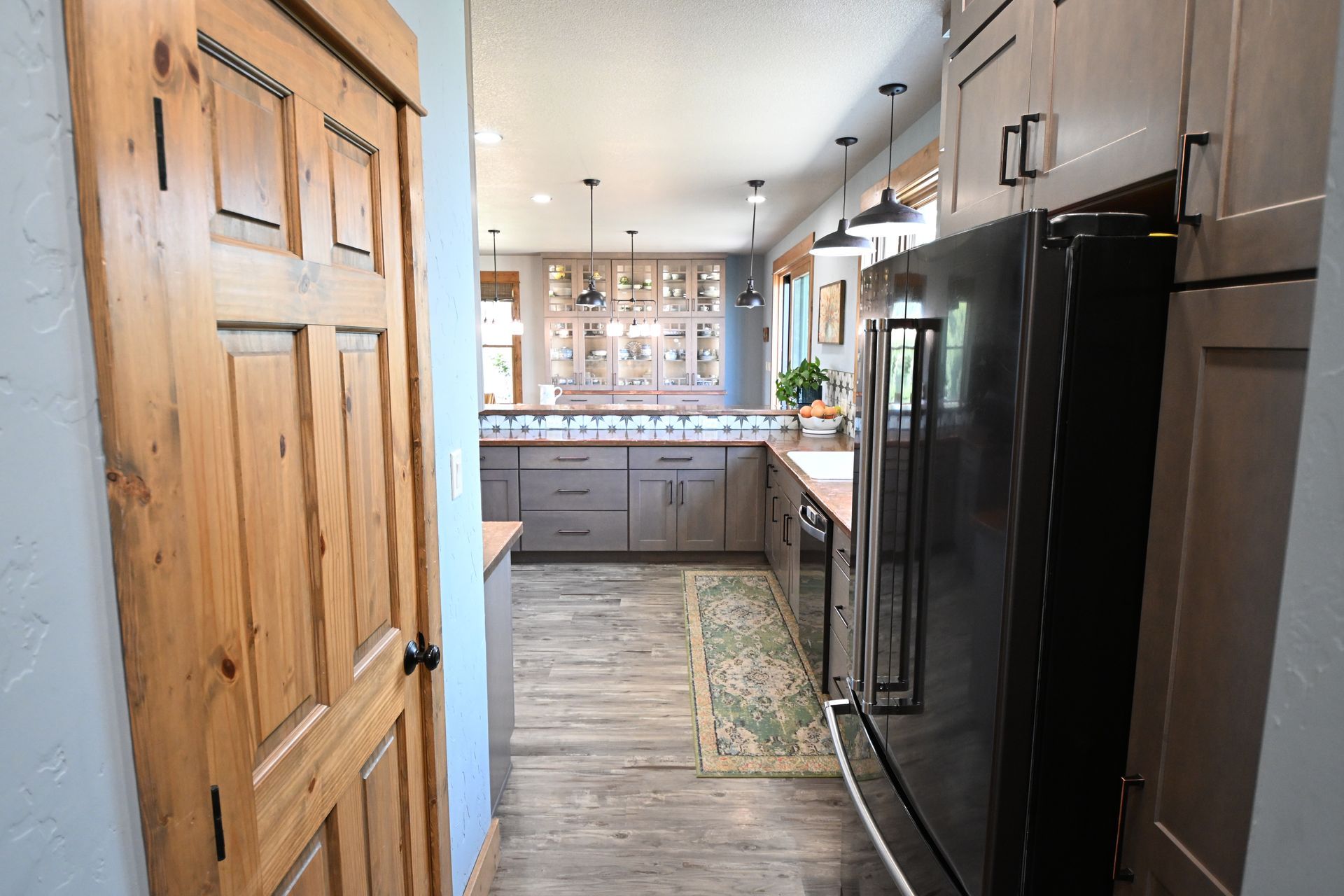Modern kitchen with wood cabinets, black appliances, and a narrow runner rug in a bright home