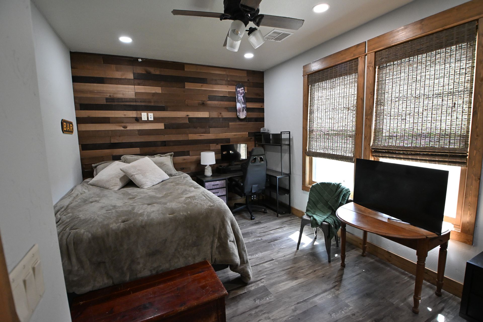 Bedroom with bed, desk, TV, and window blinds in a small, cozy room
