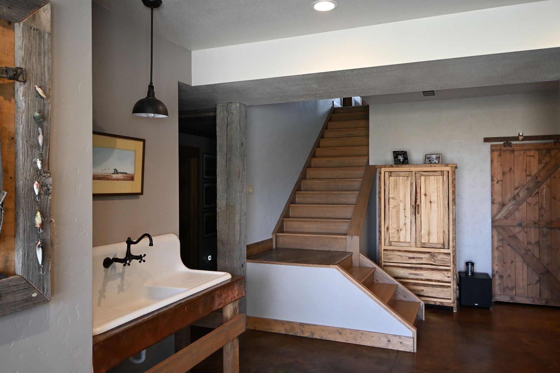 Rustic interior with wooden staircase, white sink, and tall cabinet in a softly lit hallway