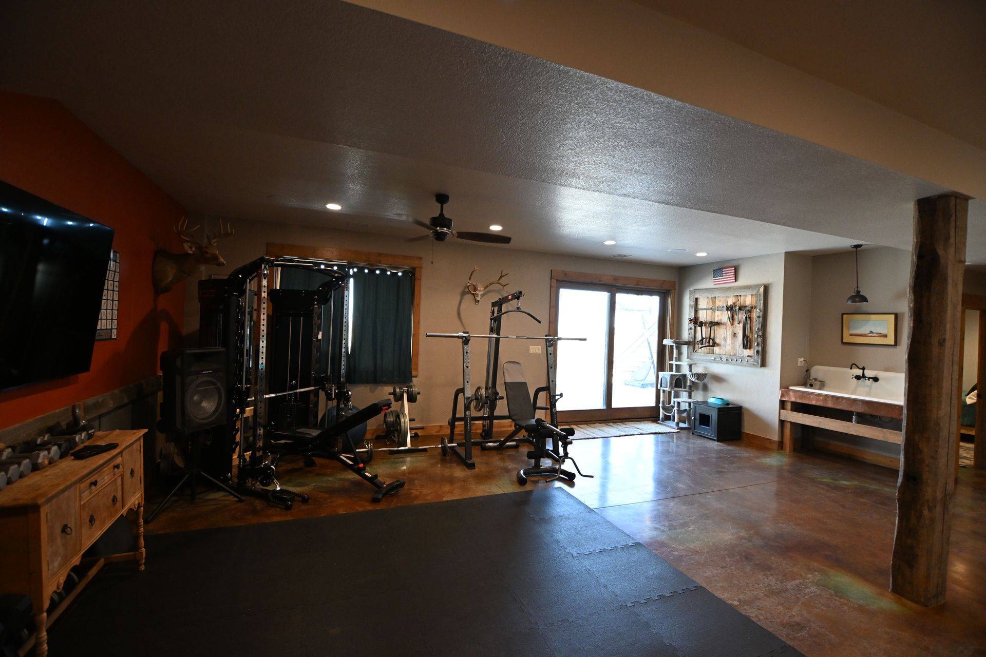 Large open living room with exercise equipment, a TV, wooden cabinets, and sliding glass doors.