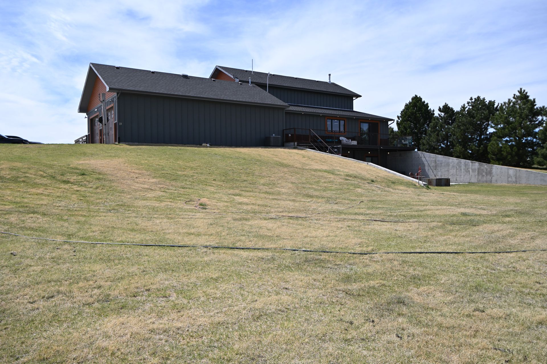 Dark house on a grassy hill under a clear sky