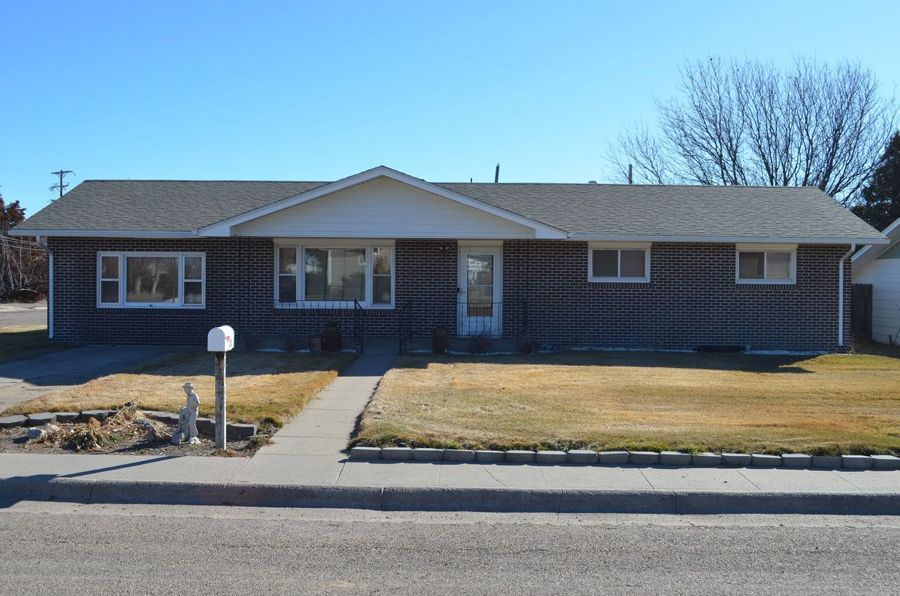 Brick ranch-style house with a pathway leading to the front door; brown lawn and clear blue sky.