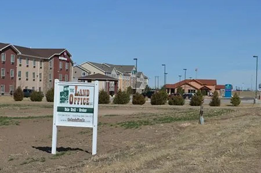 Sign for The Land Office in front of a building complex on a sunny day.