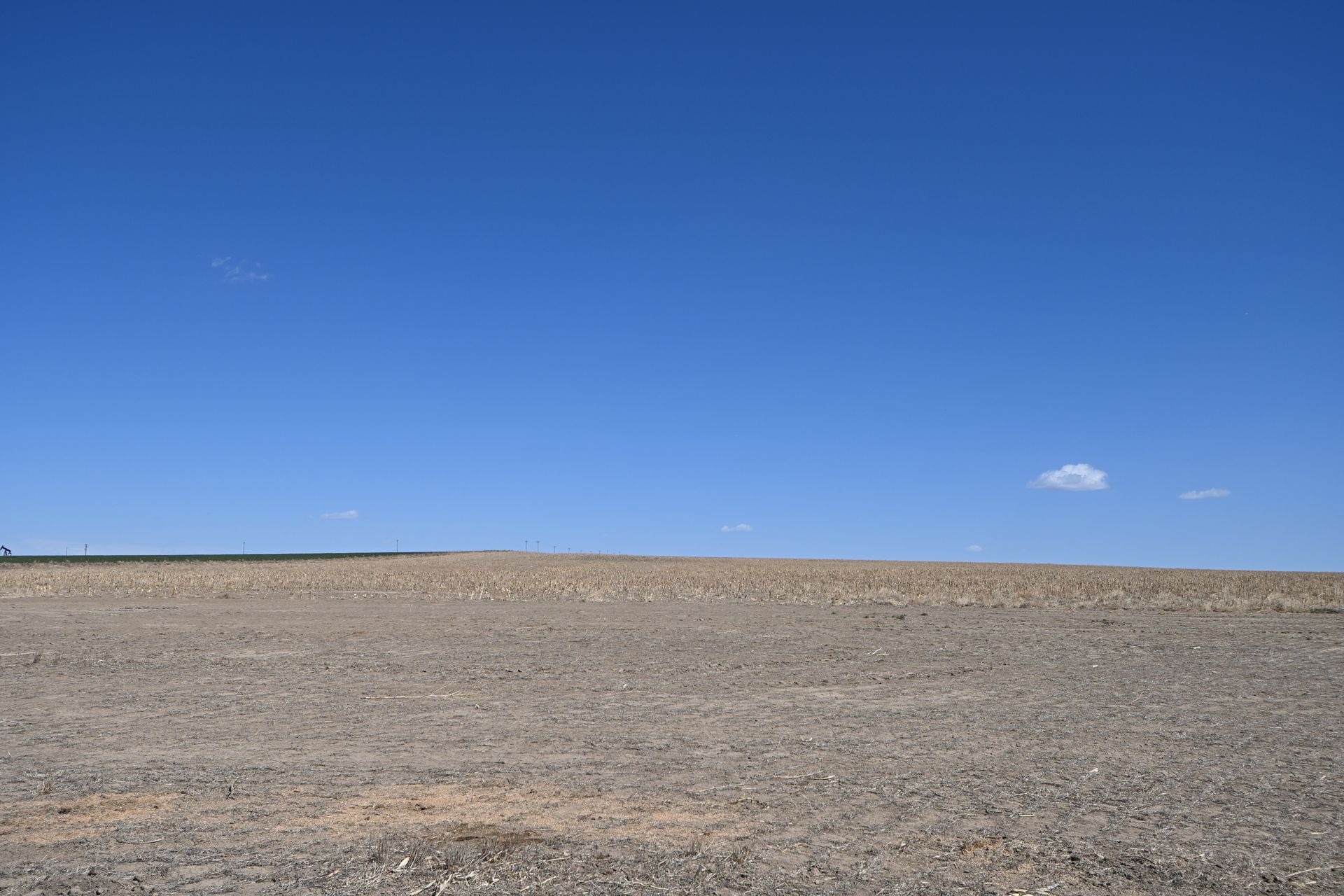Empty gravel plain under a clear blue sky with a small cloud
