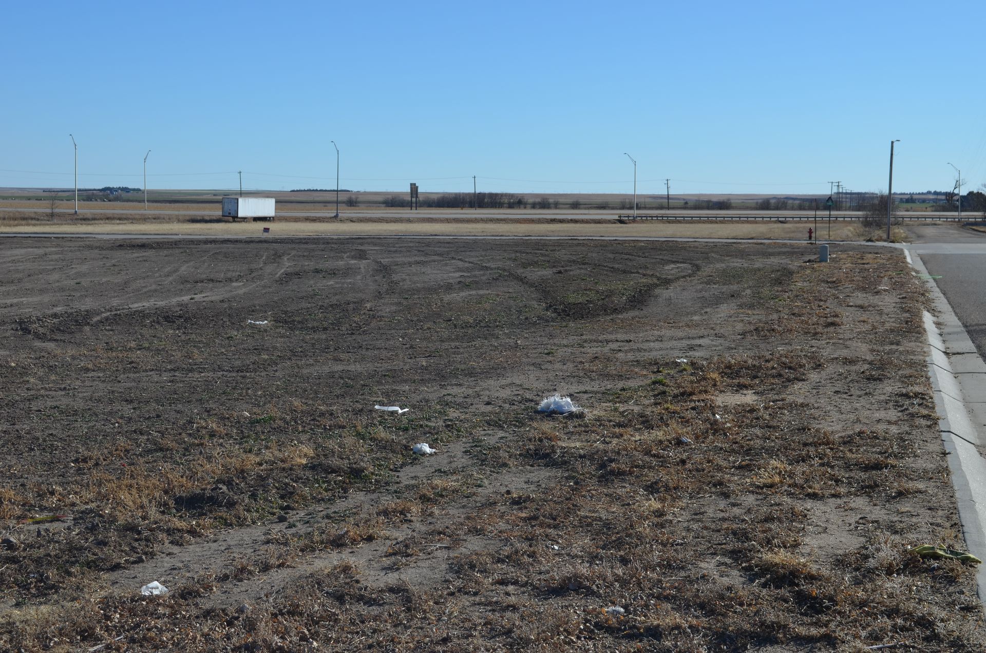 Barren land with dried grass and a road on a sunny day.