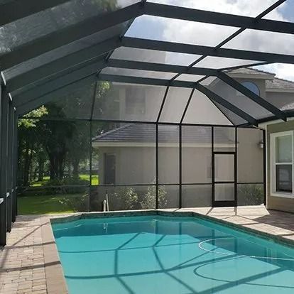 Screened-in backyard pool with a turquoise surface and tiled deck in a covered enclosure