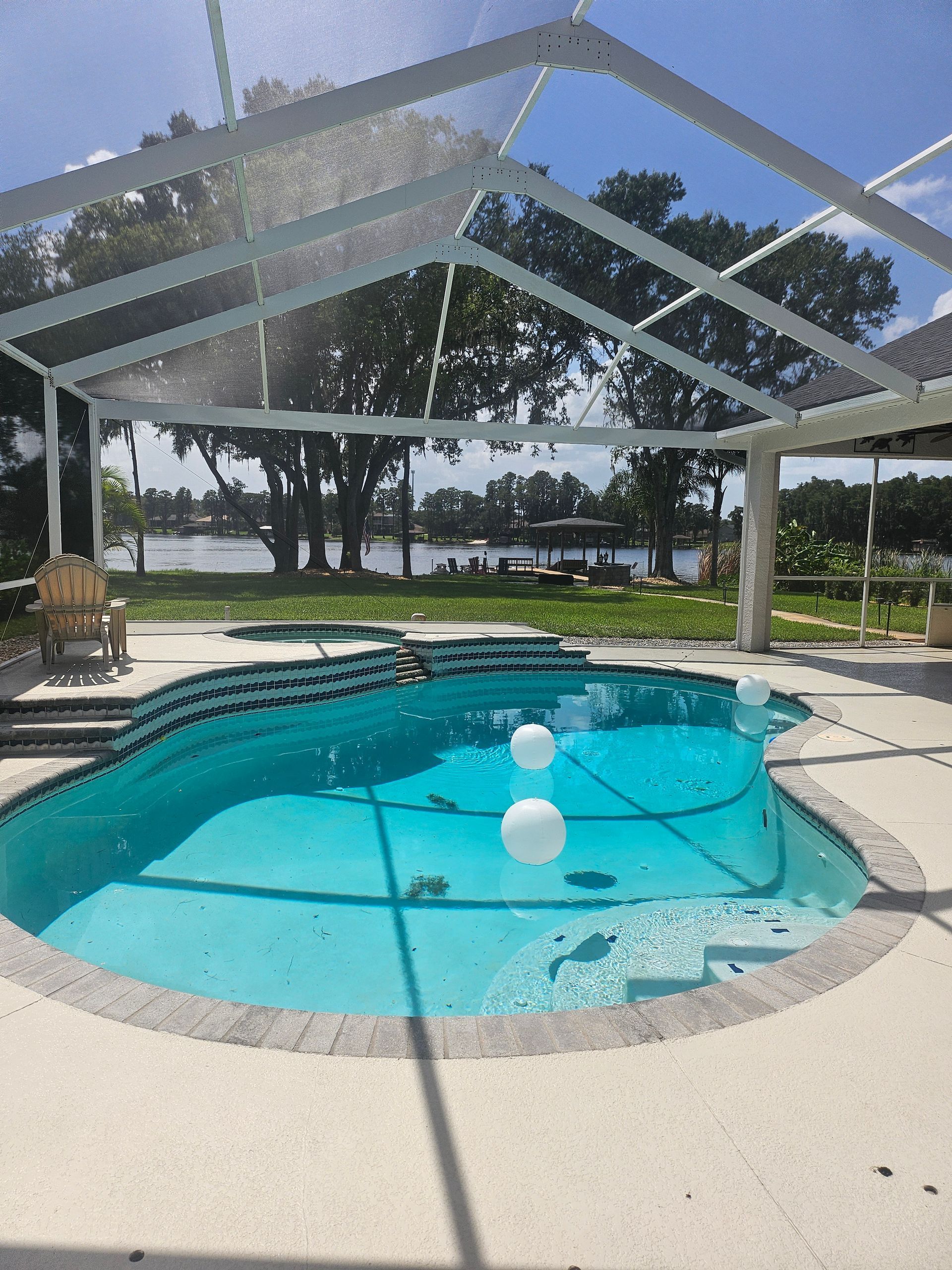 Screened-in patio with a turquoise swimming pool and bright sunlight overhead.