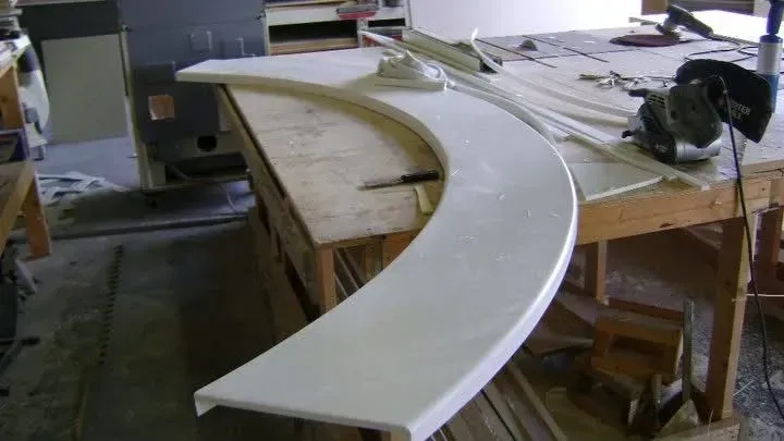 White curved countertop on a wooden workbench in a workshop.
