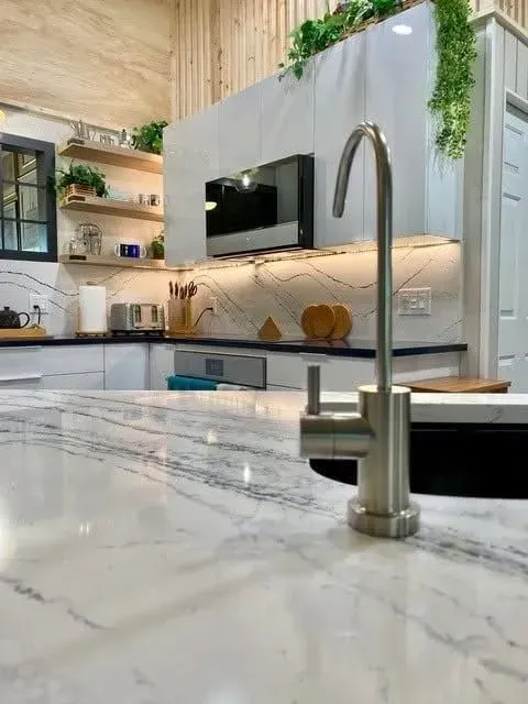 Modern kitchen with marble countertop, stainless steel faucet, and decorative shelves.