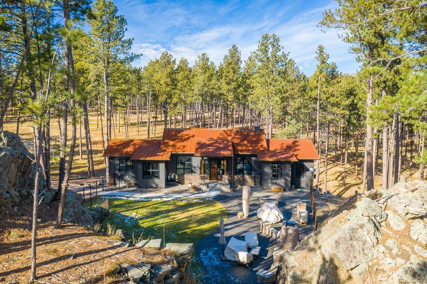 An aerial view of a house in the middle of a forest.