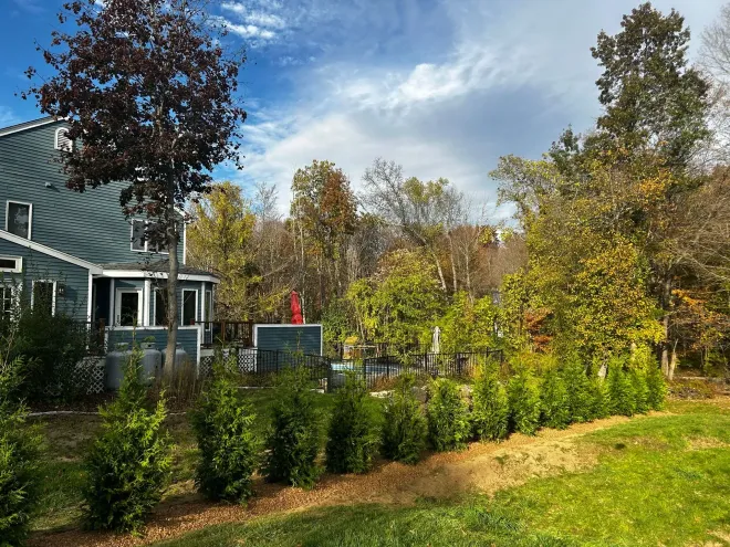 Blue house with trees and shrubs in autumn. Sunny sky.