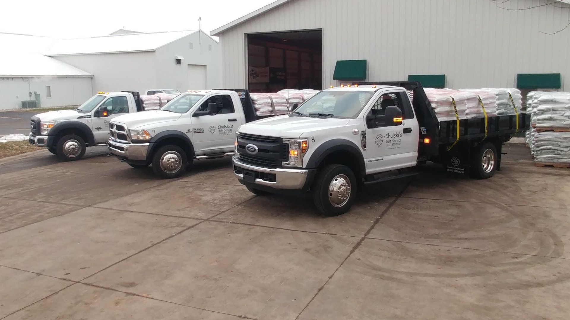 three white trucks are parked in front of a building