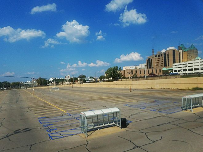 Empty rooftop parking lot with scattered carts, blue sky, and buildings in the distance