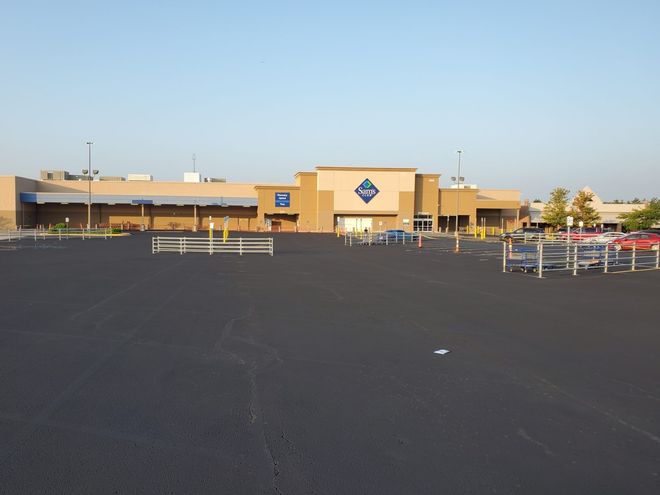 Large retail store with a parking lot and shopping carts under a clear blue sky
