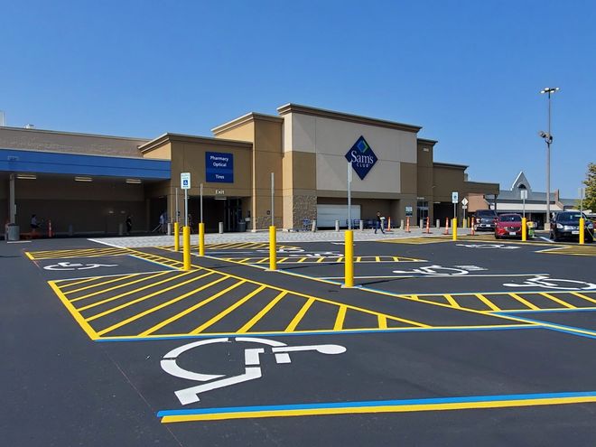 Walmart store entrance with blue handicap parking spaces and yellow crosswalk markings in front.