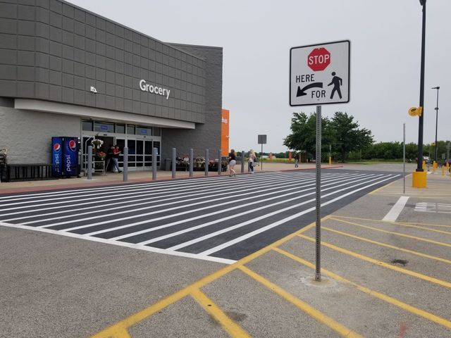 Store entrance with zebra-striped pedestrian crossing and stop sign in a parking lot.