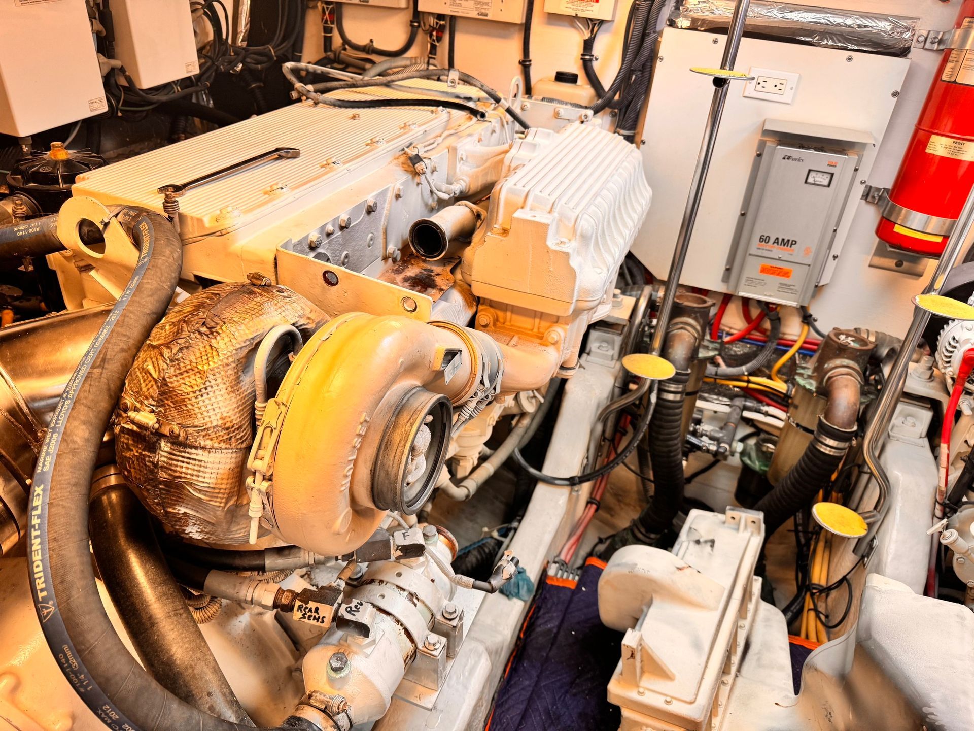 Engine room with a large diesel engine, various components, and a fire extinguisher.