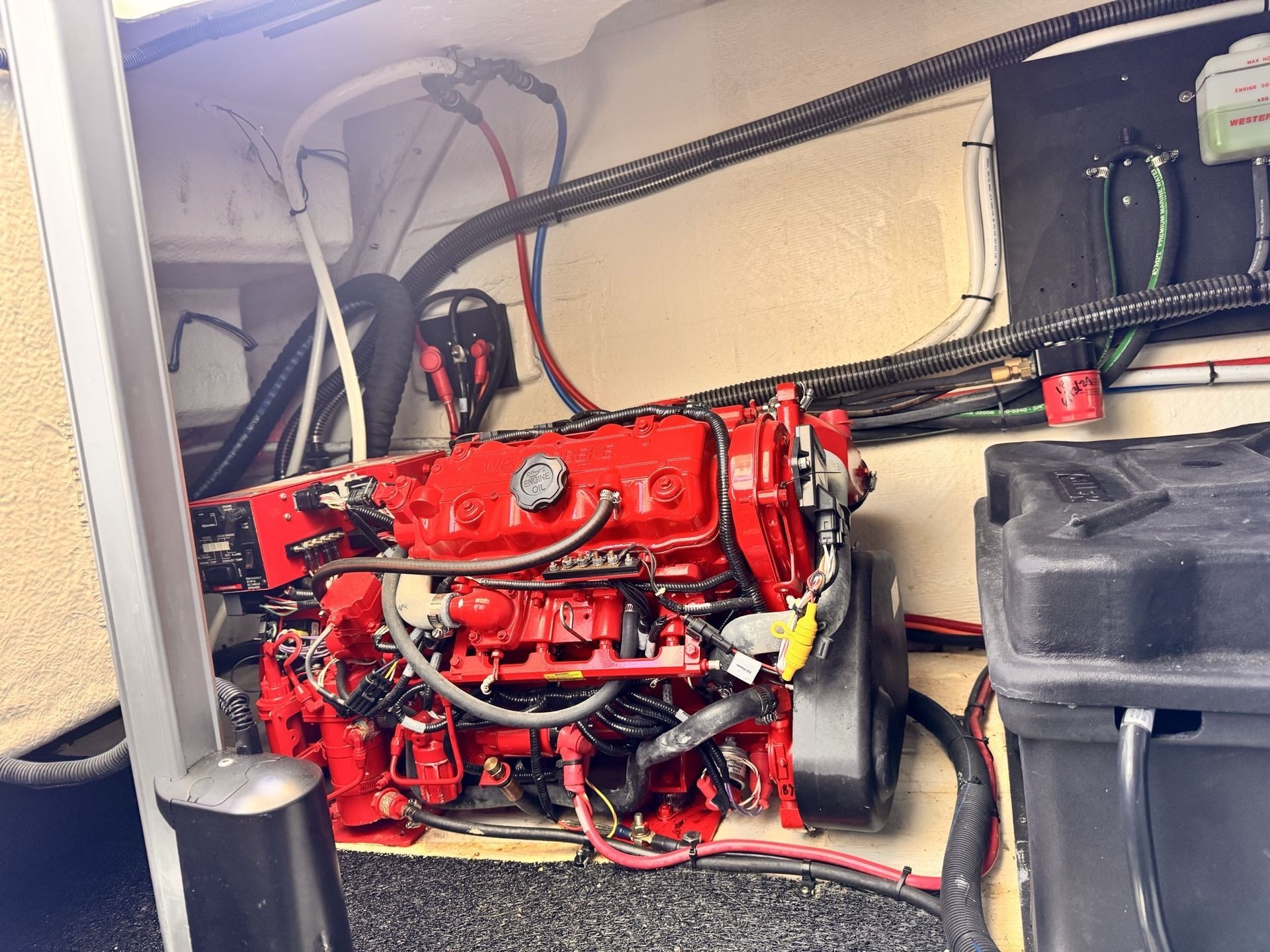 Red boat engine with black wires and a battery in a boat compartment.